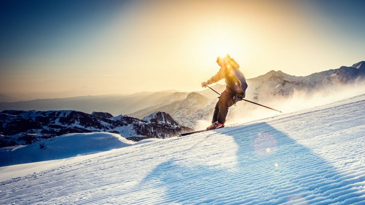 Panoramic shot of young female freestyle skier in high mountains at early morning.