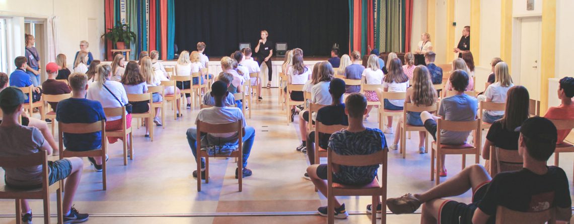 Bild bakifrån i aulan på första samlingen på Hjälmareds konfirmationsläger 2020 med stolar glest uppställda.